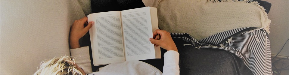 woman reading book while lying on sofa 2257043